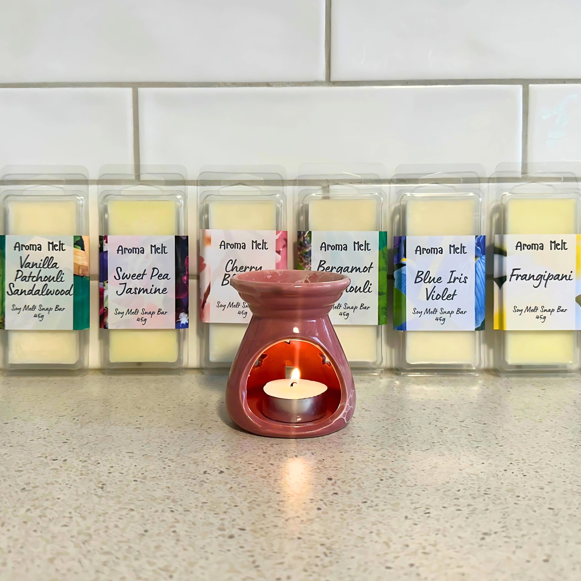  Wax warmer with a lit tealight candle melting six Aroma Melt soy wax melts in packaging, releasing fragrant aromas.